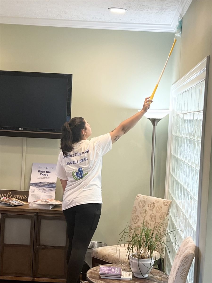Starbiz cleaner dusting high corners of a living room